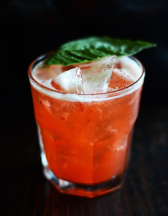 Strawberry margarita over ice with a basil leaf garnish