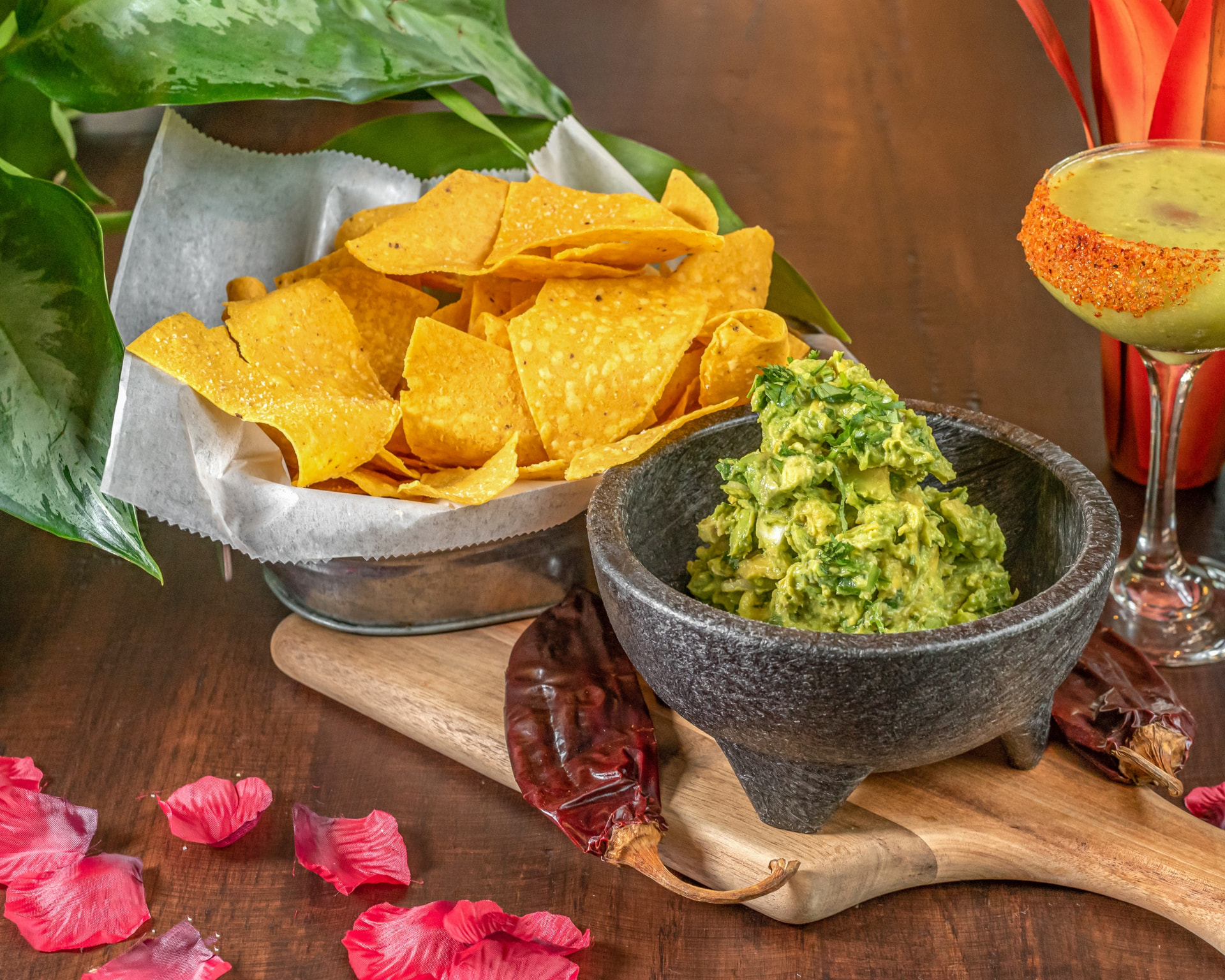 Guacamole in a stone molcajete with tortilla chips and a margarita